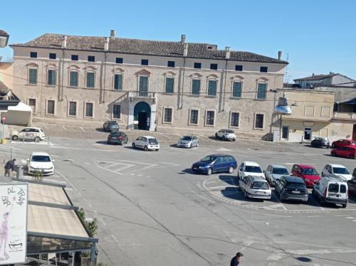 a large building with cars parked in a parking lot at HOUSE PIAZZA VITTORIA in Medole