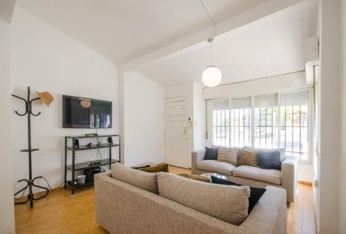 a living room with two couches and a tv at Casa en Villa Carlos Paz con Pileta , Quincho y Jardín a Pasos del Centro in Villa Carlos Paz