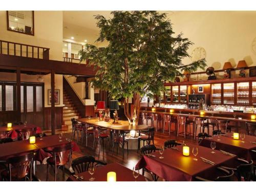un restaurant avec des tables, des chaises et un arbre dans l'établissement Boston Plaza Kusatsu Biwa Lake - Vacation STAY 15455v, à Kusatsu