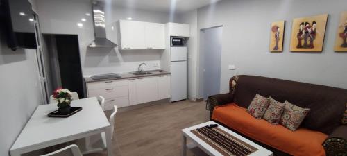 ein Wohnzimmer mit einem Sofa und einer Küche in der Unterkunft APARTAMENTO HUERTA NUEVA in Málaga