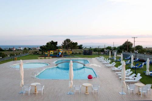 una piscina con mesas y sillas y un parque infantil en Vosporos Hotel, en Komotiní