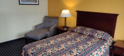a hotel room with a bed and a chair at Ashford Motel in Ashford