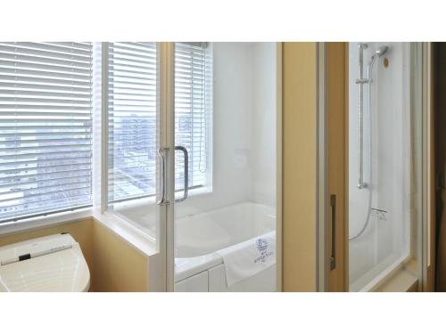 a bathroom with a tub and a toilet and a window at Boston Plaza Kusatsu Biwa Lake - Vacation STAY 15448v in Kusatsu