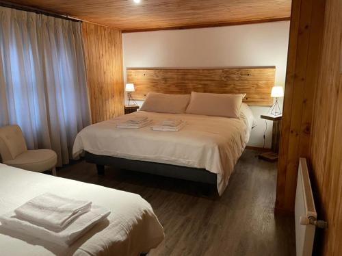 a hotel room with a bed and a chair at HOTEL VOLKANICO in Curacautín