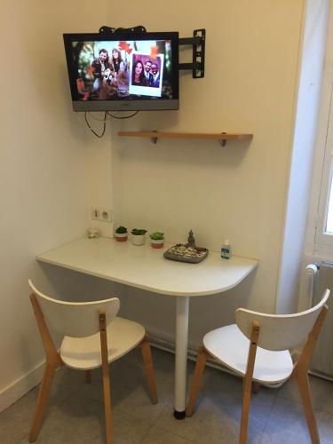 d'une table et de deux chaises avec une télévision murale. dans l'établissement Studio centre ville avec ascenseur 3min des thermes, à Aix-les-Bains
