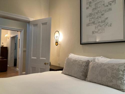 a bedroom with a white bed with a light on the wall at 3 Queen Street in Calitzdorp