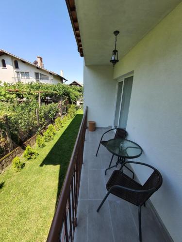 a balcony with a glass table and a chair at Дамяновата къща in Sapareva Banya