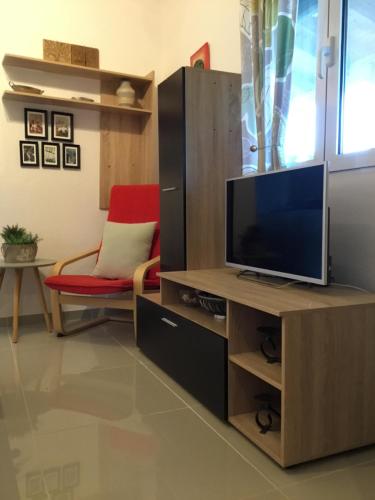 a living room with a television on a wooden cabinet at Casa dei fiori in Asprovalta