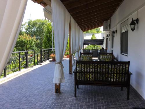 a porch with a bench and curtains on a balcony at Casa dei fiori in Asprovalta