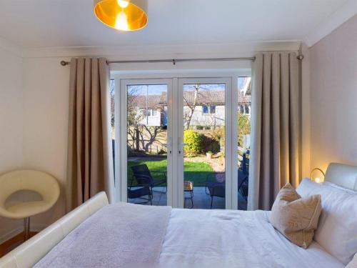 a bedroom with a white bed and a sliding glass door at Scotchacre Kingsbarns - Walk to Beach & Golf Club in Kingsbarns