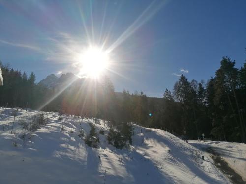 a sun is shining over a snow covered slope at Appartement Naturnah in Mieders