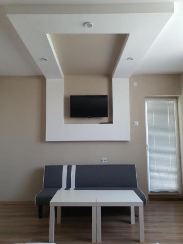 a living room with a bench and a tv on the wall at Дамяновата къща in Sapareva Banya