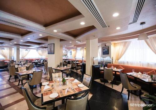 uma sala de jantar com mesas e cadeiras num restaurante em Garden Hotel Muscat By Royal Titan Group em Mascate