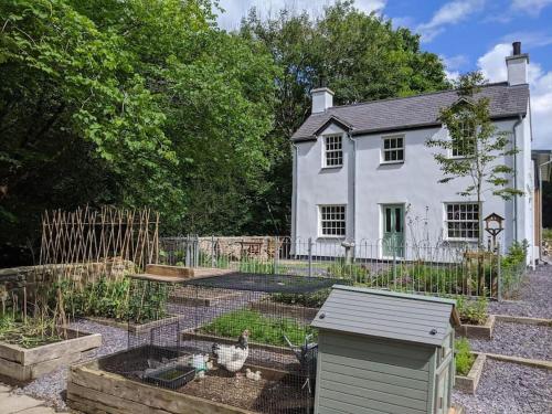 a garden with a bird cage in front of a white house at Riverside cottage walking distance into Caernarfon in Caernarfon