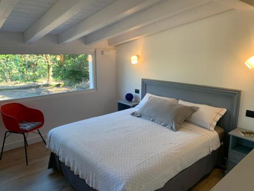 a bedroom with a bed and a red chair and a window at Il Giardino Segreto Gardasee Ferienhaus in Manerba del Garda