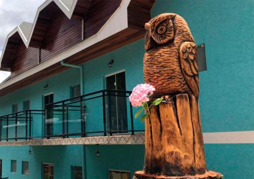 une statue d'un hibou avec une fleur devant un bâtiment dans l'établissement Pousada Alpes Azul, à Campos do Jordão