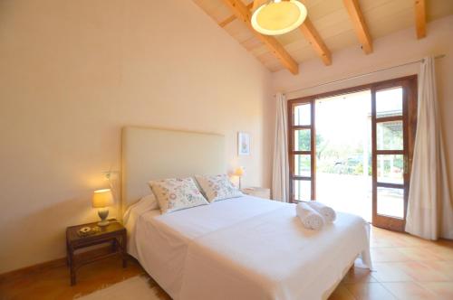 a bedroom with a white bed and a large window at Es camp den Gall in Santa Eugenia