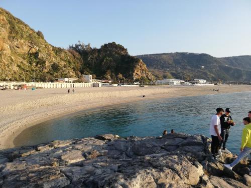 a group of people standing on the rocks at the beach at Appartamento City in Palmi