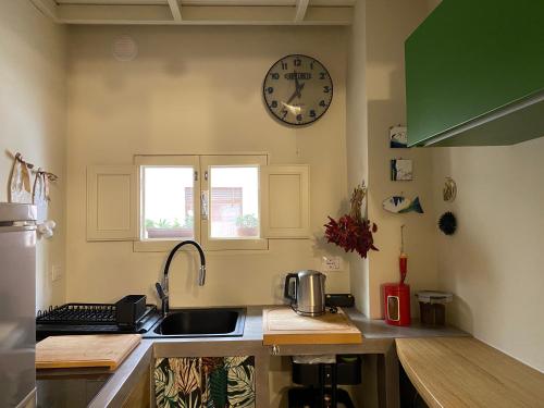 Una cocina con un fregadero y un reloj en la pared. en Casa VicoloLungo Nardó, en Nardò