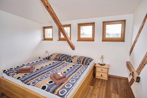 a bedroom with a bed with a comforter and three windows at Strnadovský mlýn in Jesenice