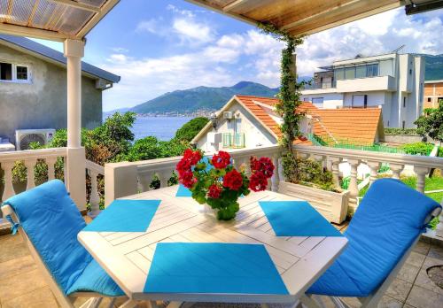 a table with blue chairs and a vase of flowers on a balcony at Bayview Apartments in Tivat