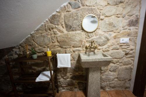 a stone bathroom with a sink and a mirror at A de Pepita, turismo rural en Padrón. in Padrón