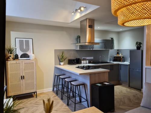 a kitchen with a island with bar stools at Modern 1 bed apartment next to beach and golf course in Llanelli