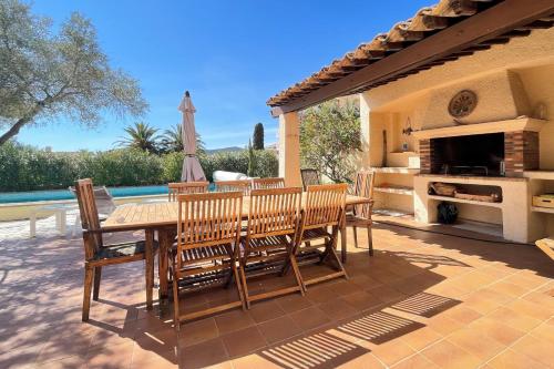a patio with a table and chairs and a fireplace at villa for 10 people with private pool 250m from the sea in Saint-Aygulf