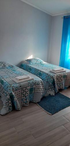 a bedroom with two beds and a table on a rug at Casa da Aldeia in Santa Clara-a-Nova