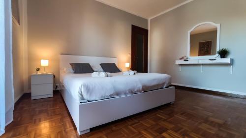 1 dormitorio con 1 cama blanca grande y espejo en Da Vinci's House, a due passi dalla Reggia, en Venaria Reale