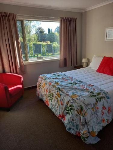 1 dormitorio con cama, silla roja y ventana en b&b @ fynnz, en Turangi