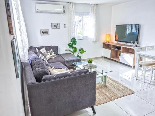 a living room with a couch and a tv at Fully Equipped In A Central Location in Eilat