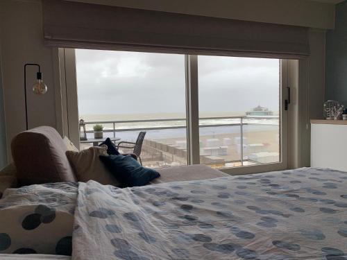 a bedroom with a bed and a view of the ocean at LECOMTE Zeedijk Blankenberge in Blankenberge