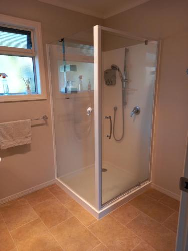 a shower with a glass door in a bathroom at b&b @ fynnz in Turangi