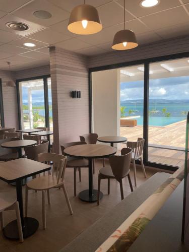 a restaurant with tables and chairs and a view of the ocean at B&B HOTEL Fort-de-France in Fort-de-France