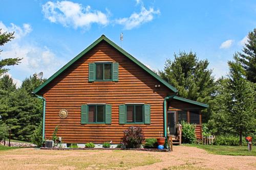 a small wooden house with green shutters on it at RTLCMP Lakehouse in Arbor Vitae