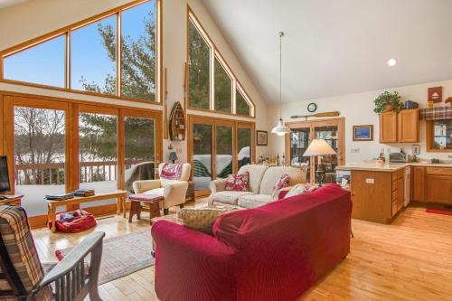 a living room with a red couch and a kitchen at RTLCMP Lakehouse in Arbor Vitae