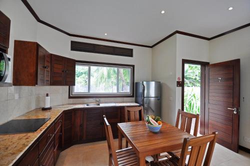 a kitchen with a wooden table with chairs and a kitchen with a refrigerator at Cote d'Or Footprints in Baie Sainte Anne