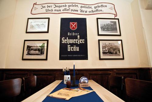 una mesa en un restaurante con un cartel en la pared en Schwerter Schankhaus & Hotel, en Meißen