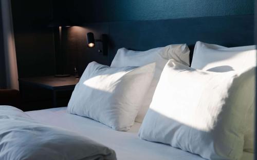 a bed with white pillows and a blue head board at Best Western Plus Oslo Airport in Gardermoen