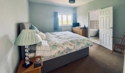a bedroom with a bed and a lamp and a bathroom at Chadwell Hill Farm in Longwick