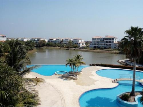 un complexe avec 2 piscines plantées de palmiers et une rivière dans l'établissement Condominio Campestre Laguna Club Cartagena, à Los Arrayanes