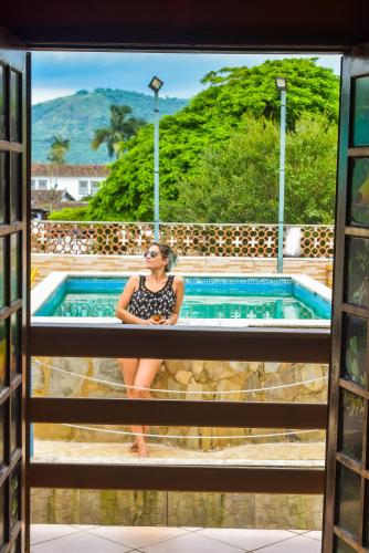 a woman sitting on the ledge of a swimming pool at Leo's Clan Beach Hostel in Paraty