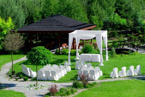 a group of white chairs and a gazebo at Hotel & Restauracja Okrąglak in Chęciny
