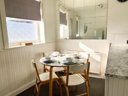 een keuken met een tafel met stoelen en een spiegel bij Cheerful 2 bedroom residential home - Free parking in Leeds
