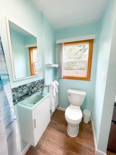 a bathroom with a toilet and a sink and a window at The Anchorage Motel in Pacific City
