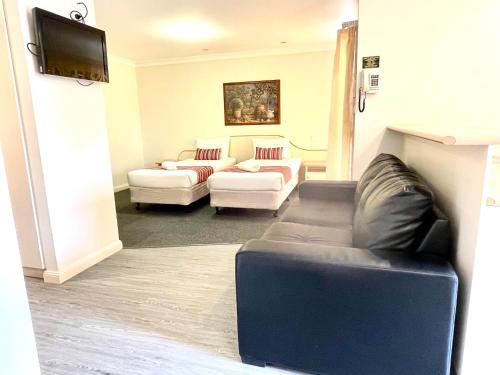 a living room with two couches and a flat screen tv at Golfview Motor Inn in Wagga Wagga
