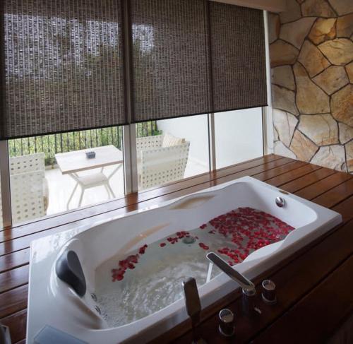 a bathroom with a bath tub filled with red roses at TS SUITES Seminyak Bali in Legian