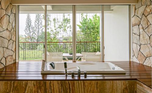 a bath tub in a room with a large window at TS SUITES Seminyak Bali in Legian