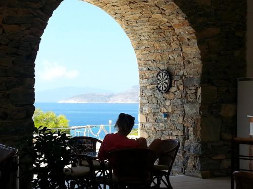 een vrouw in een stoel die uitkijkt op de oceaan bij Archipelagos Boutique Hotel in Skhoinoussa